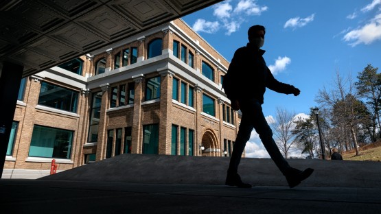 A student passes by Rand Hall on a clear spring day.