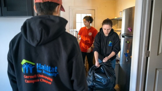 Cornell Habitat for Humanity members help move items out of a house in preparation for construction.