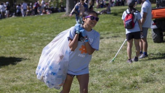 A volunteer carries a bag of recyclables. 