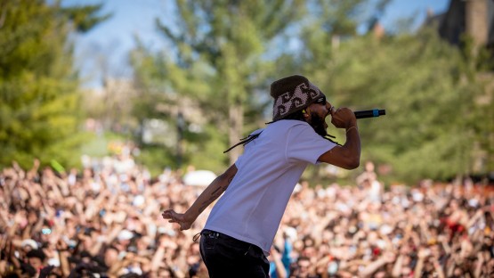 Performer singing into a microphone to a packed crowd. 