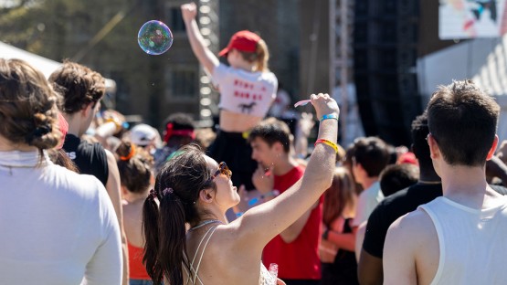 A student blows soap bubbles in the crowd. 
