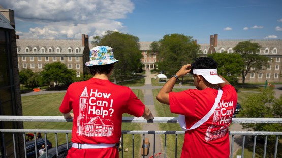 Two student volunteers look out over the railing towards the residence halls. 