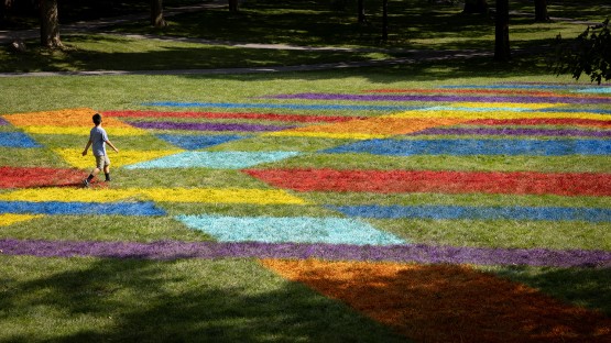 A visitor explores a colorful lawn painting on the Arts Quad.