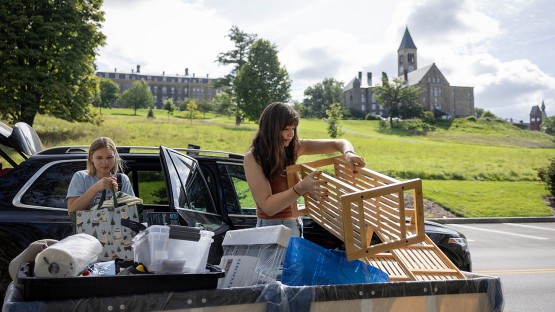 Two young women loading belongings into a moving cart. 