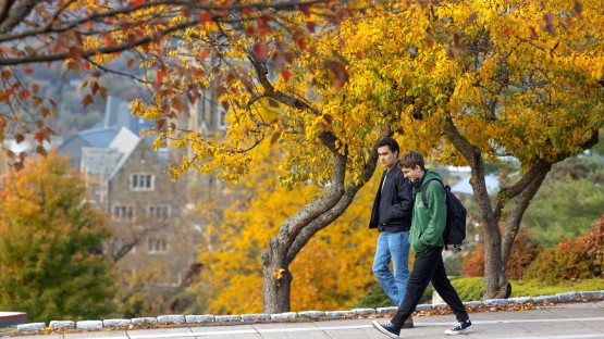 Students walk between Willard Straight Hall and Uris Library on an autumn day.