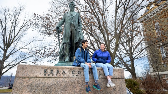 Friends hang out near the Ezra Cornell statue on the Arts Quad