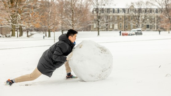 A student makes a snowman on the Arts Quad.