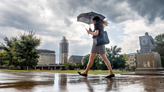 Woman walks through campus during rainstorm