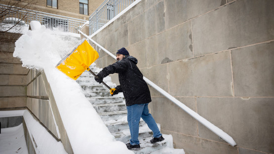 A building care staffer clears steps near Mann Library.