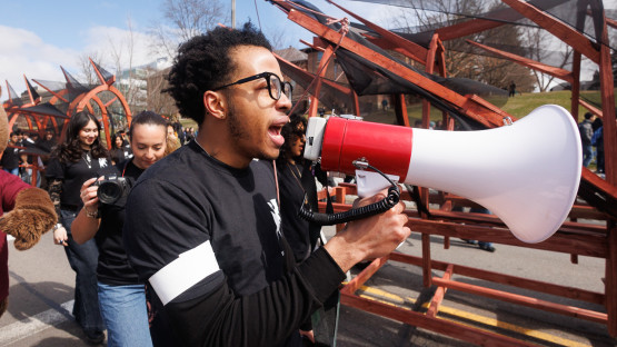 A student on a megaphone walking with the dragon. 