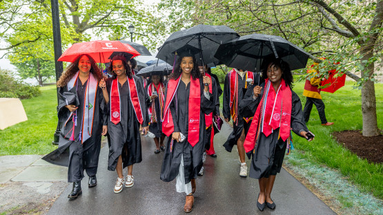 Students walking across campus in the rain, holding umbrellas. 