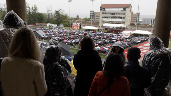 Families in rain gear looking out at the field. 