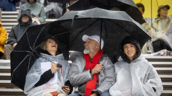 A family in the stands under umbrellas. 