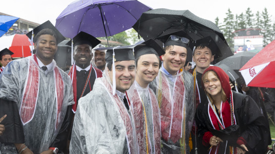 Students on the field posing for a rainy picture. 