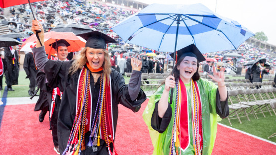 Two graduates cheering while leaving the field. 