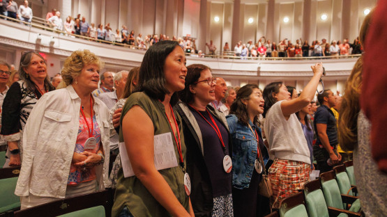 Reunion 2026 attendees stand in an auditorium
