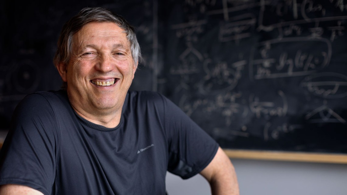 Yuval Grossman smiles in portrait in front of chalkboard