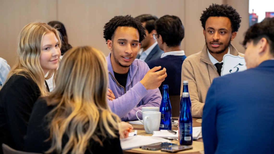 SC Johnson College student Jason DeLaCruz ’26 (in purple) speaks with mentors and students at a recent Accelerator Scholar event at KKR in New York City. 