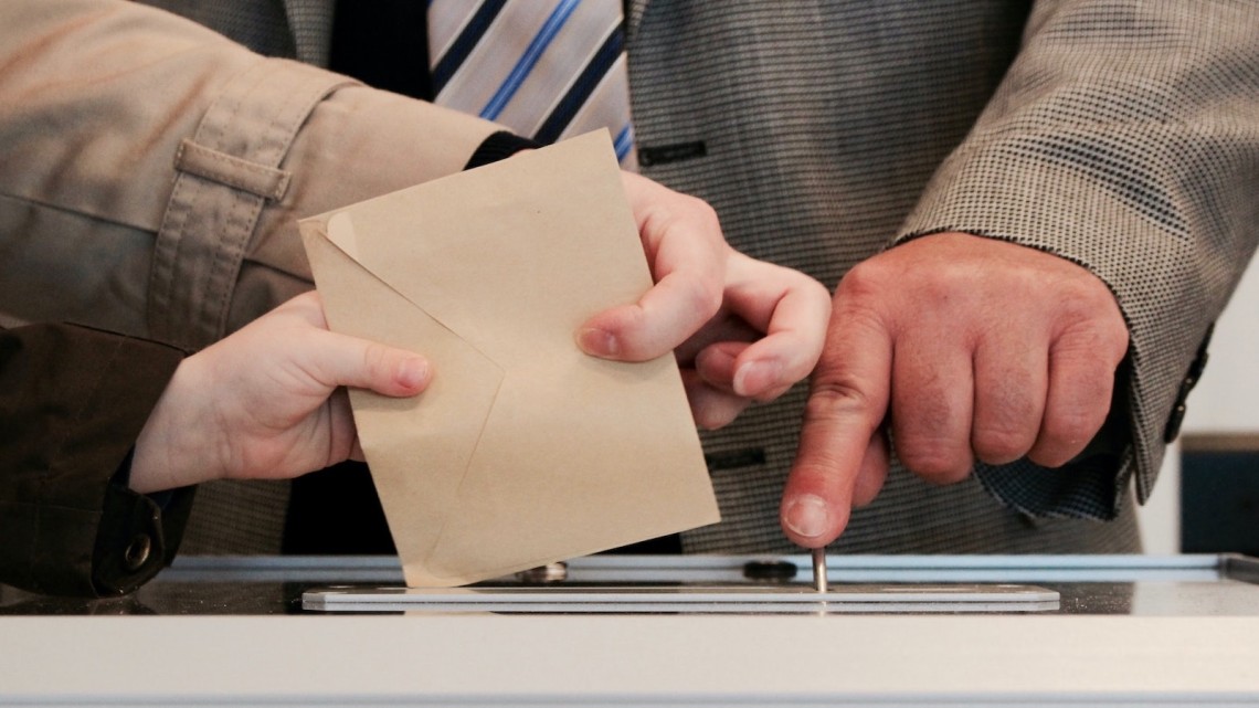three hands struggling at ballot box