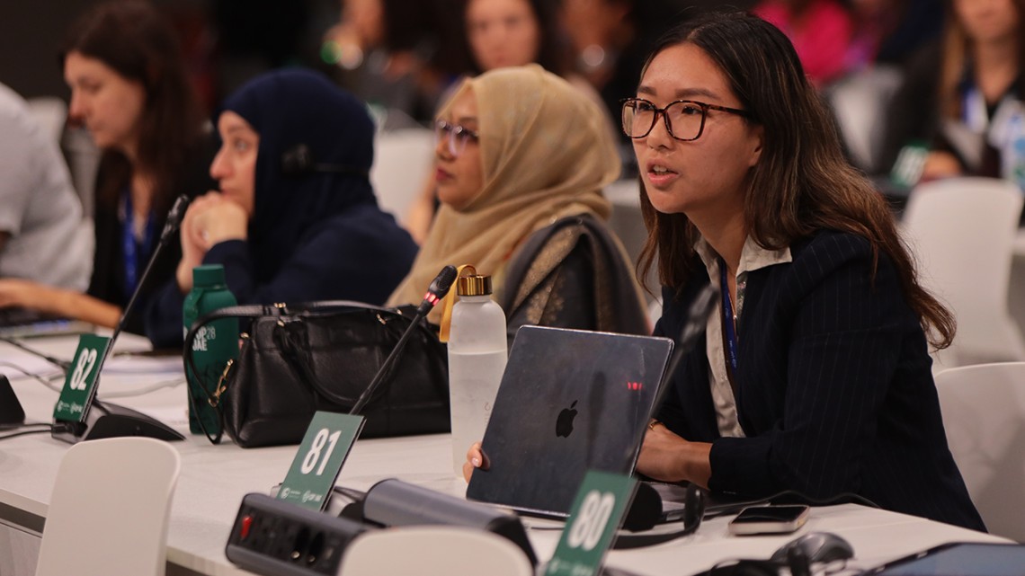 Cynthia Tan '26 speaks at panelist table microphone at the COP28 Conference
