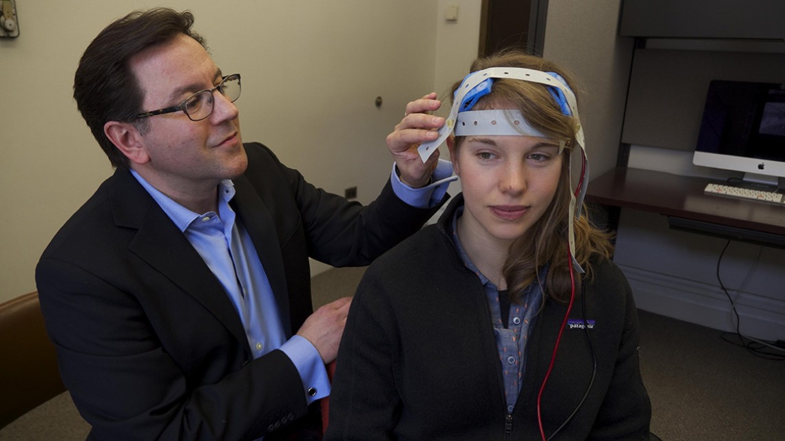 Daniel Casasanto adjusts electrodes on the scalp of a study participant