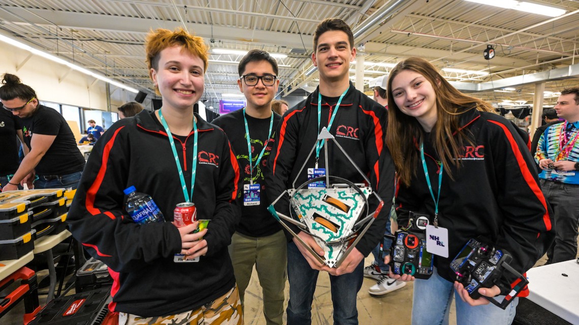 four students hold a robot