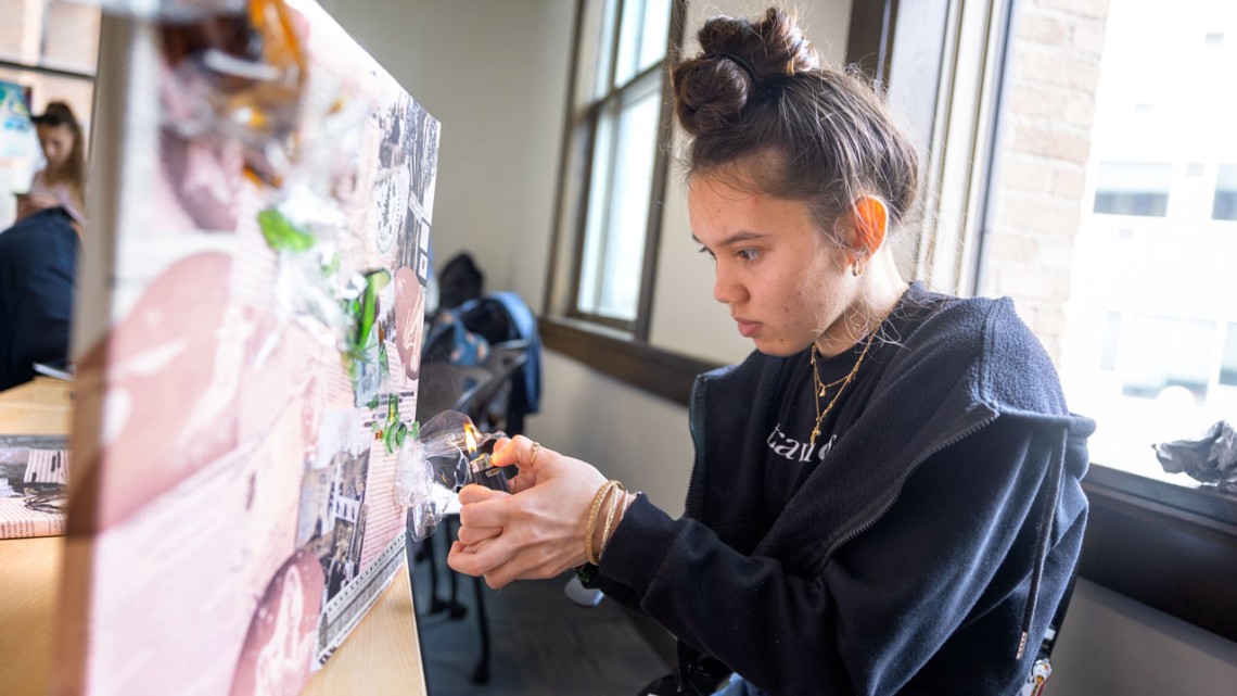 Kailee Tomas uses a lighter to melt plastic litter collected from the Mohawk River.