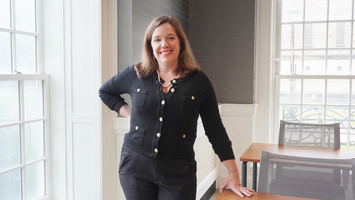 Colleen Carey leans on a desk in a classroom