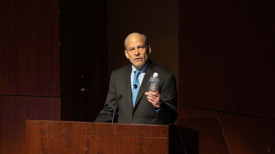 A man standing behind a podium and speaking.