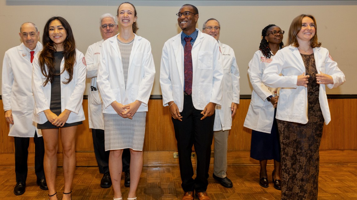 Medical students don their white coats with a little help from faculty