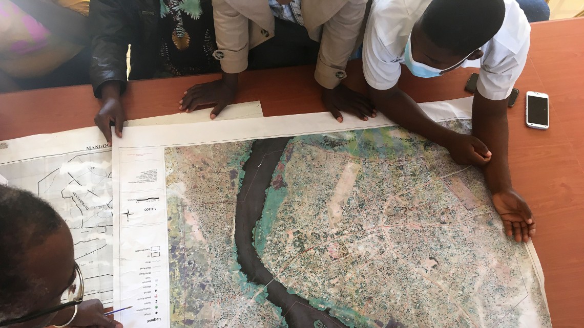 A group of people crowd around at a map with a river, the photo is taken from above.
