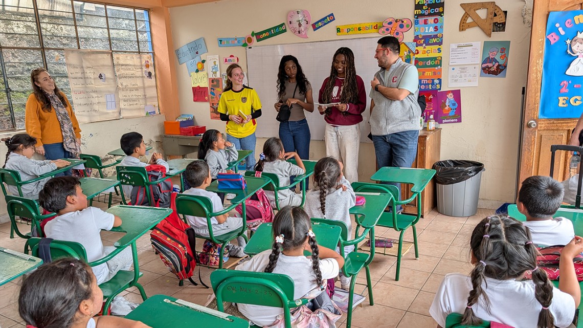 Cornell and Universidad San Francisco de Quito (USFQ) students in a classroom interacting with elementary school students at their desks 
