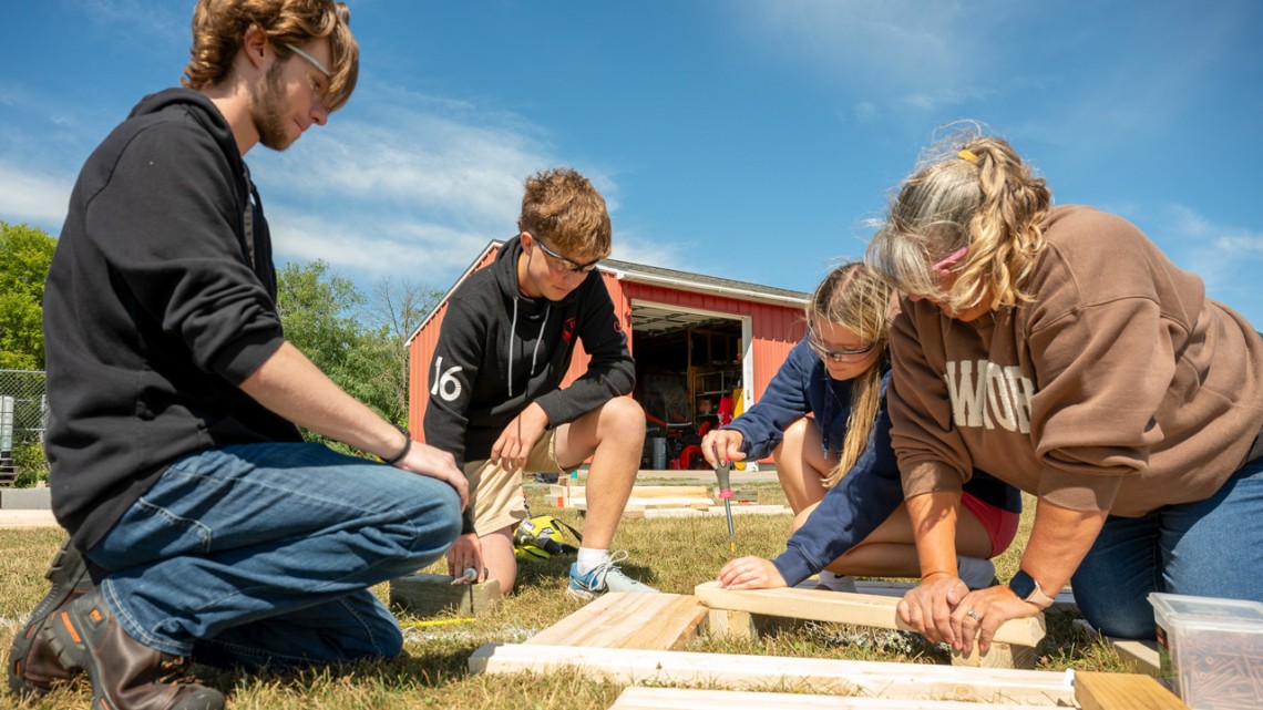 Cornell Cooperative Extension Jefferson County community school coordinator Donna Jean Coleman (right) helps LaFargeville Central School students Alexander Moore (far left), Samuel Duffany and Ella Hunneyman screw together boards on a flower box they built for a student-led community beautification project.