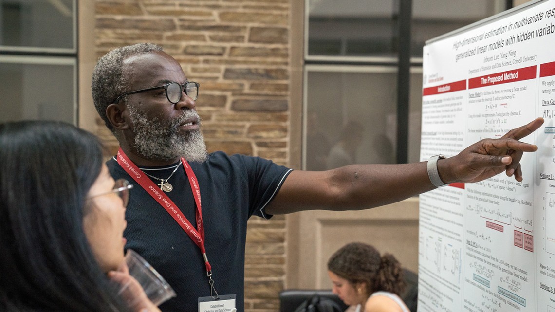 Two conference attendees discuss a poster.