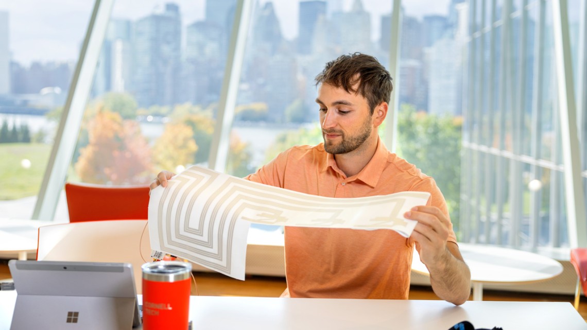 Thomas Conroy, Ph.D. ’24, holds up a version of the SensVita device that can be attached to furniture.