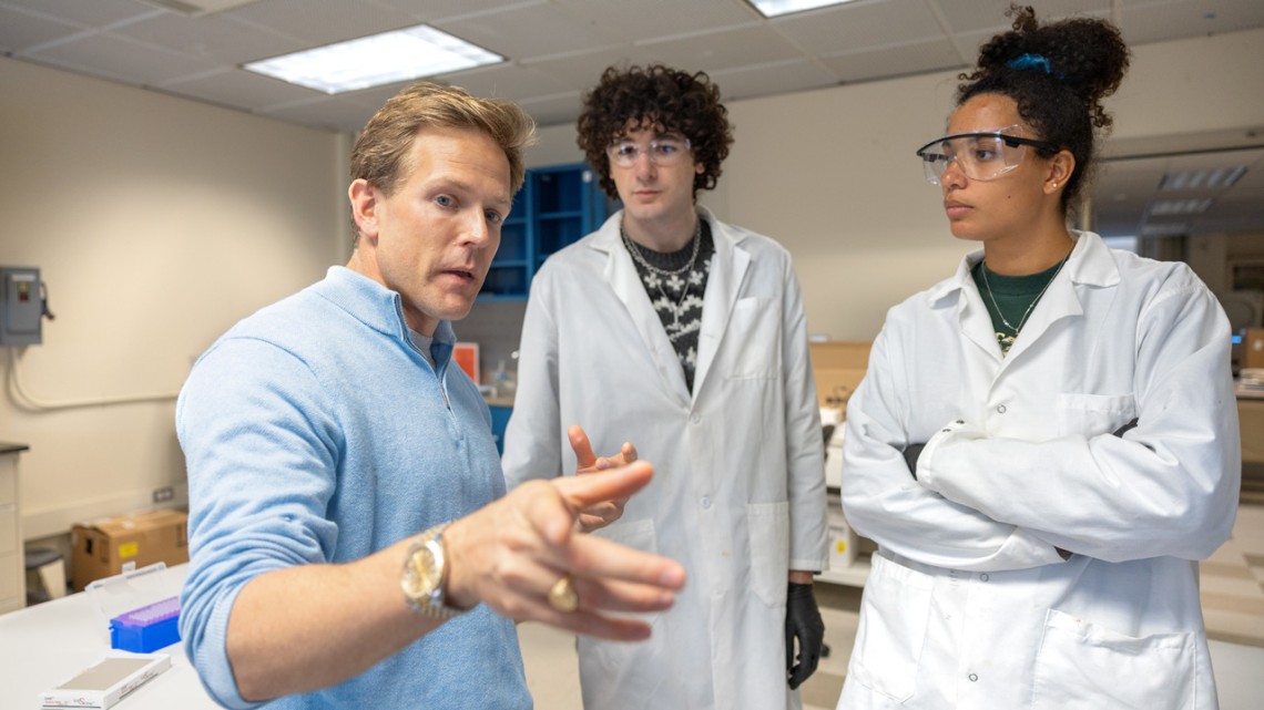 Quantera founder Terry Bates, Ph.D. ’23, explains the operation of the startup's spectrometer to undergraduate interns Nick DeMayo and Alexis Sherman