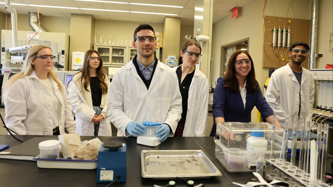 Cornell and Queen Mary University of London collaborators wear white lab coats and protective goggles. 