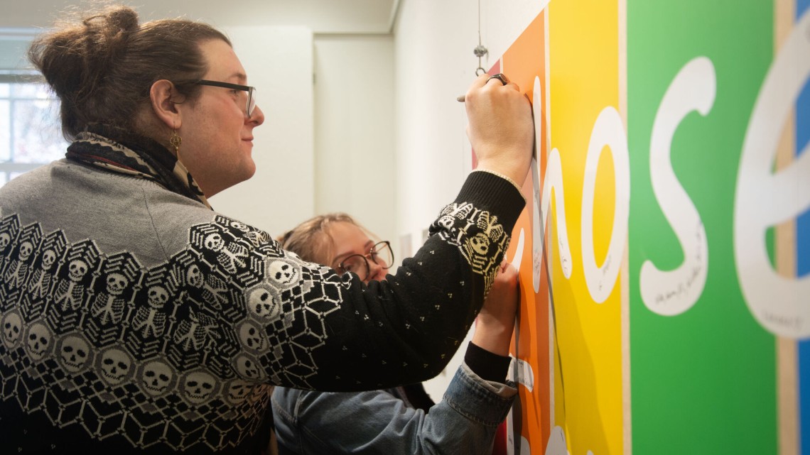People write on a "chosen family" banner