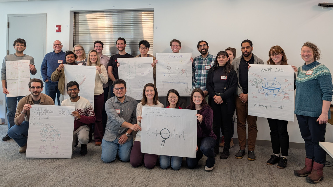 22 people pose in a group holding signs