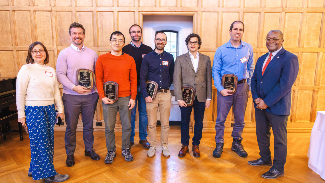 eight people pose with plaques