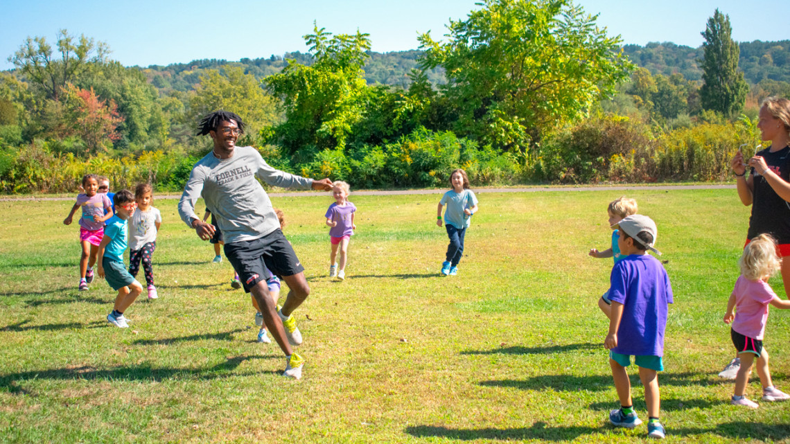 Noah Cummings ’26 avoids participants during a warmup activity during a session of Run Your City, a six-week youth sports camp, at Cass Park in Ithaca.