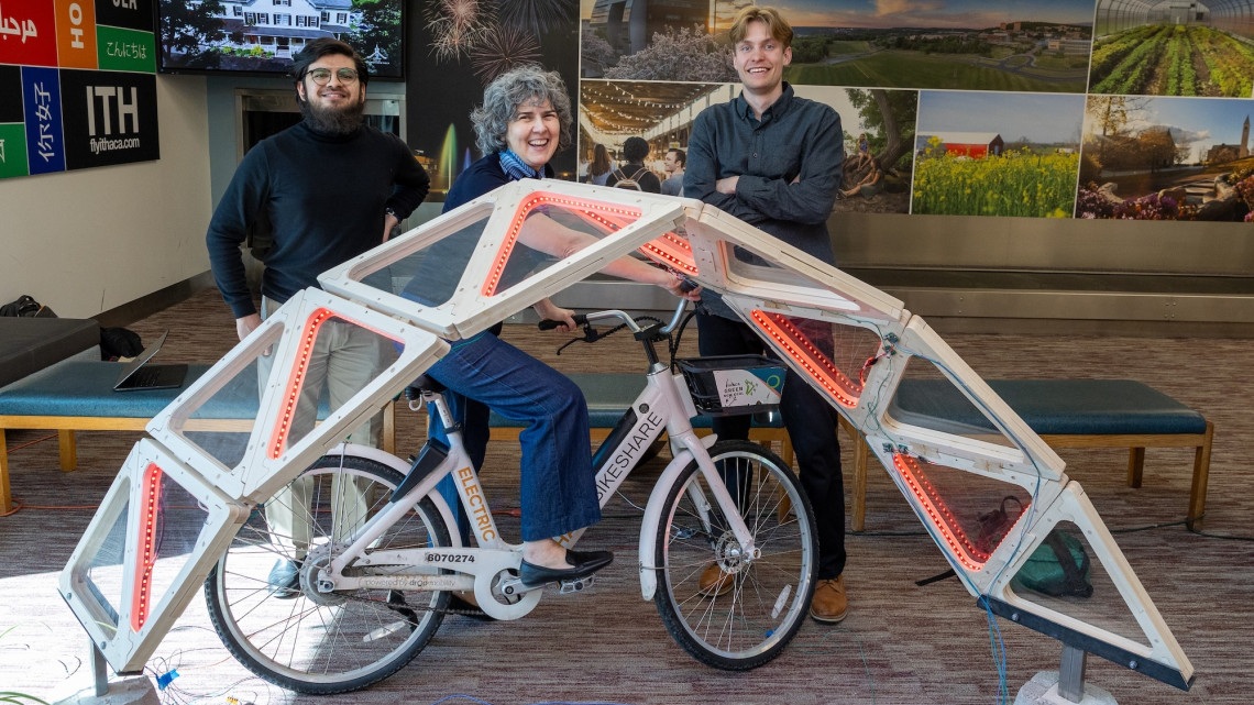 three people pose behind an LED arch