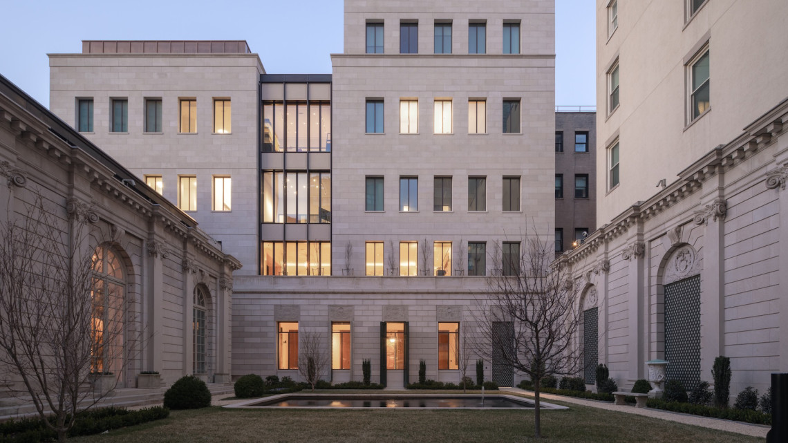 Large stone building at dusk with pool in front.