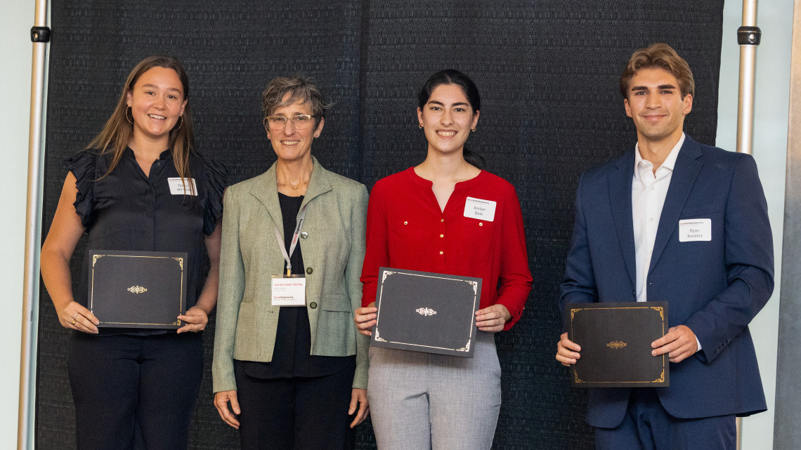 four people stand together holding certificates