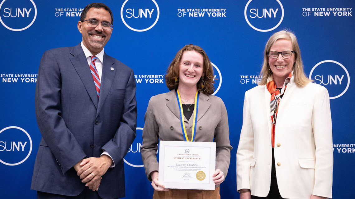 Three people posing with award certificate