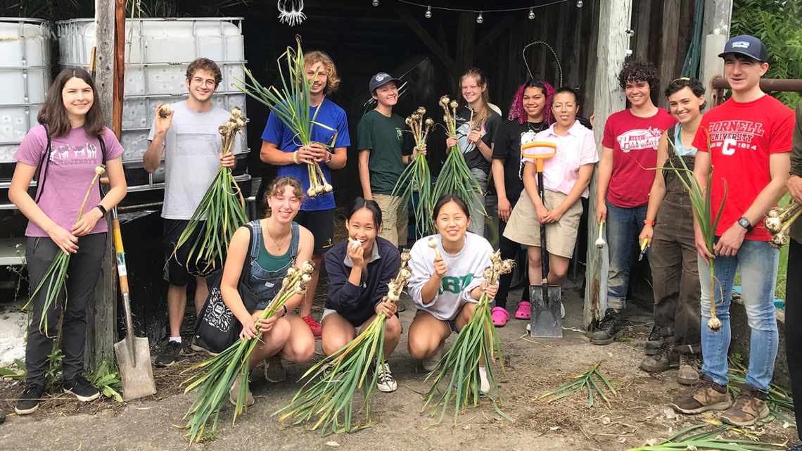 A group of students holding newly harvested garlic