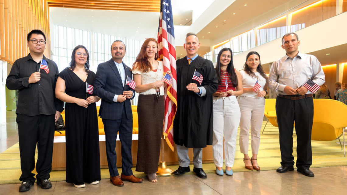 At center, Scott A. Miller ’90, J.D. ’95, acting New York State Supreme Court justice and Tompkins County court judge, celebrates with the eight immigrants who became U.S. citizens at a naturalization ceremony held July 23 at the College of Veterinary Medicine. Miller had presided over the ceremony.