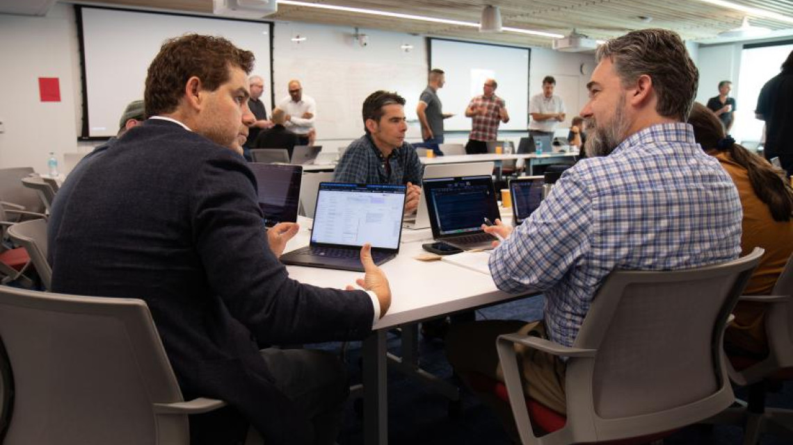 Two people in deep discussion, at a table in front of laptops