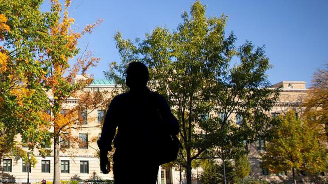 A silhouette of a student walking on the ag quad in the fall