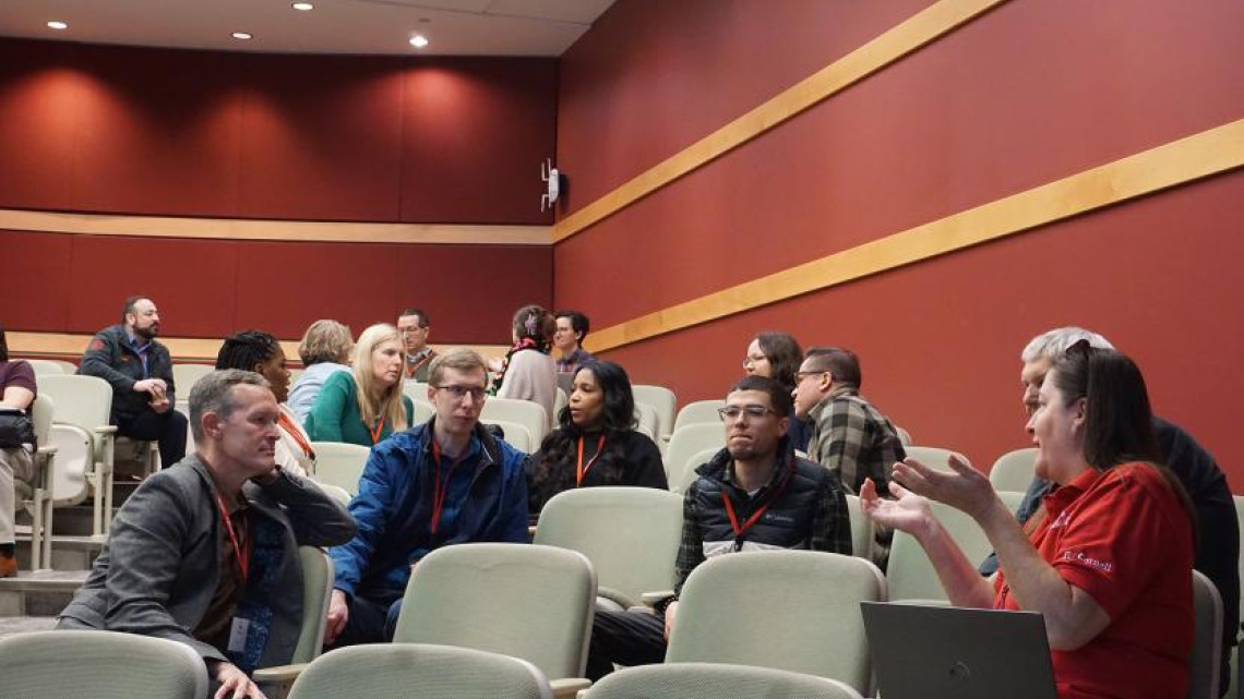 Breakout participants in a conference room speak with one another